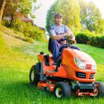 Gardener driving a riding lawn mower in garden