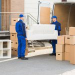 Movers Carrying Sofa Outside Truck On Street